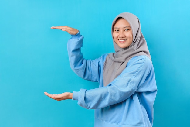 Foto hermosa mujer asiática alegre en suéter azul mostrando un espacio de copia