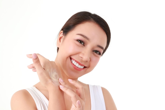 Hermosa mujer asiática aplicando crema para la piel en el brazo para realzar su belleza. Ella cuida la salud de su piel para que sea suave, brillante, saludable, natural, concepto de belleza, cuidado de la salud. Fondo blanco.