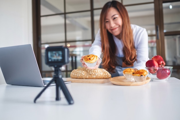 Una hermosa mujer asiática blogger de comida o vlogger grabando un video en la cámara