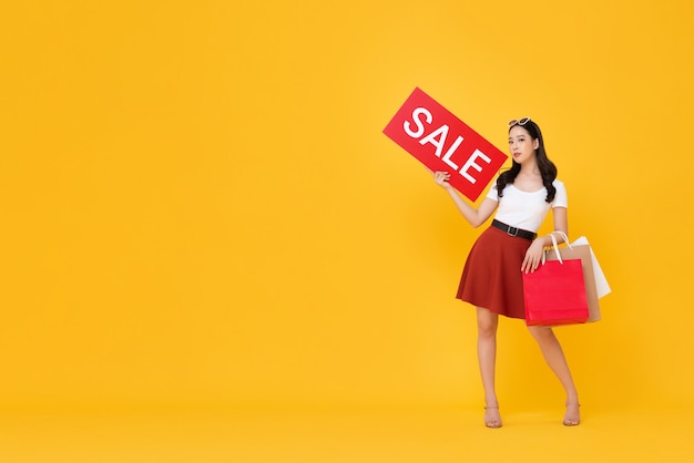 Hermosa mujer asiática con bolsas de la compra con cartel de venta rojo