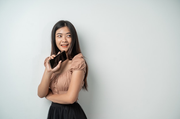 Hermosa mujer asiática con cabello largo se siente muy feliz cuando sostiene un teléfono inteligente