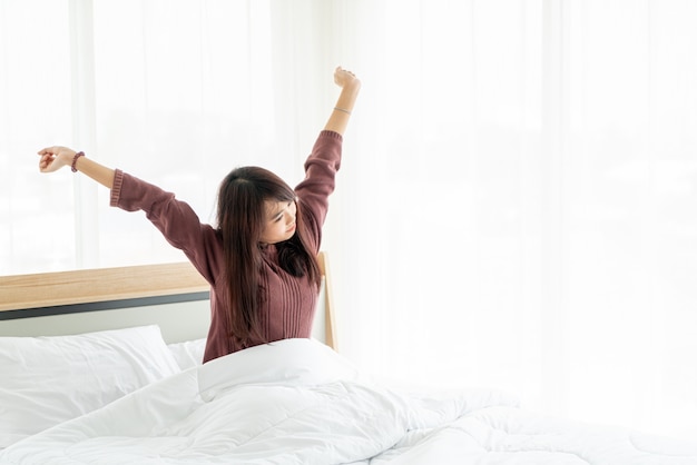 Hermosa mujer asiática en la cama y despertarse por la mañana