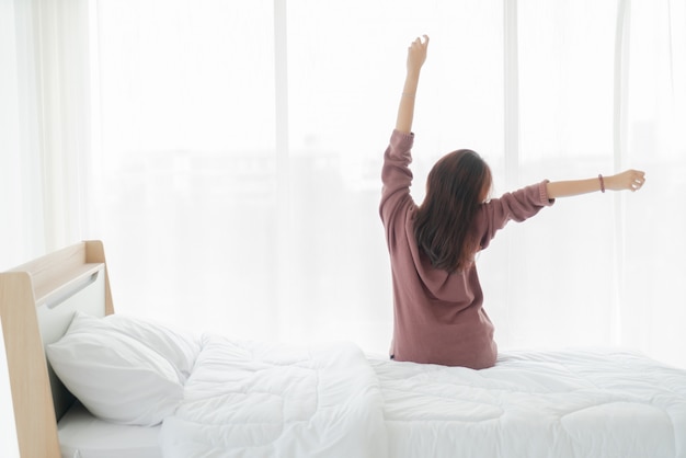 Hermosa mujer asiática en la cama y despertarse por la mañana