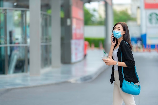 Hermosa mujer asiática caminando para ir a trabajar Joven mujer de negocios exitosa en una gran ciudad Nueva normalidad