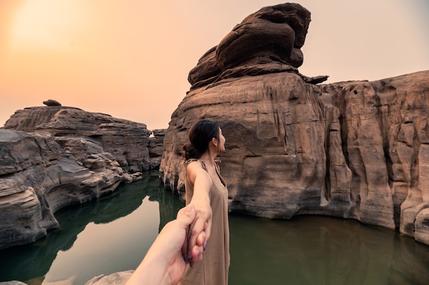 Hermosa mujer asiática cogidos de la mano con la pareja en la garganta de roca del gran cañón en la noche