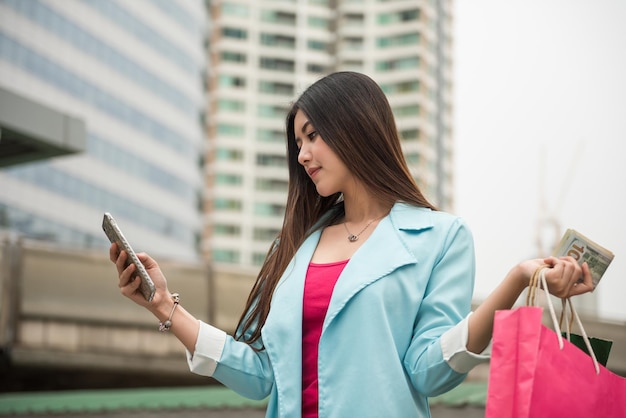 Foto una hermosa mujer asiática conversa o envía un mensaje de texto con una amiga sobre ventas en la ciudad