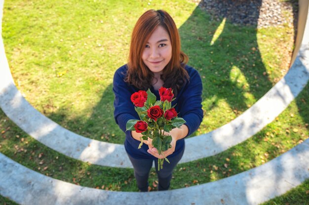 Una hermosa mujer asiática dando flores de rosas rojas a su novio el día de San Valentín con sentimiento feliz y amado