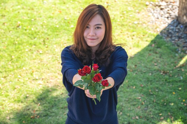 Una hermosa mujer asiática dando flores de rosas rojas a su novio el día de San Valentín con sentimiento feliz y amado