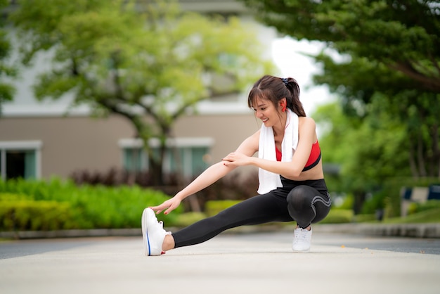 Hermosa mujer asiática ejercicio estiramiento solo en parque público en la aldea, feliz y sonrisa en la mañana durante la luz del sol. Modelo de fitness deporte etnia asiática formación concepto al aire libre.