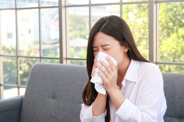 Hermosa mujer asiática enferma de gripe tiene la nariz tapada Sostenga un pañuelo para cubrirse la boca. Evite que el virus se propague. concepto de salud