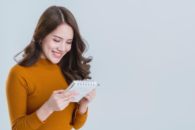 Hermosa mujer asiática escribe una nota en papel con felicidad y momento alegre aislar fondo blanco