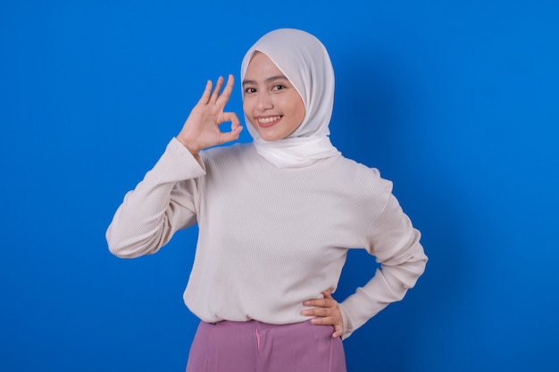 Hermosa mujer asiática con expresión de sonrisa de camiseta blanca larga con su mano