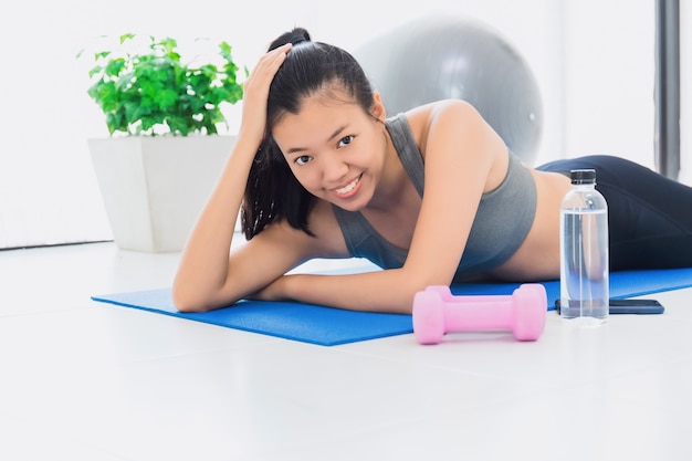 Hermosa mujer asiática feliz descansando en el ejercicio de la estera de yoga