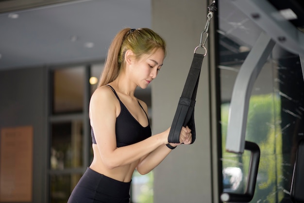 Una hermosa mujer asiática fitness está entrenando con equipamiento deportivo en el gimnasio. Concepto de fitness y salud.