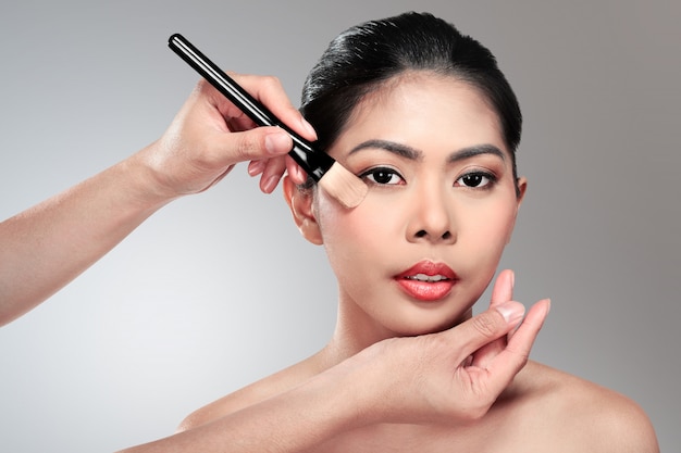 Hermosa mujer asiática haciendo maquillaje