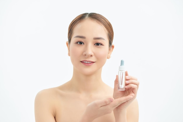 Hermosa mujer asiática joven que muestra el producto para el cuidado de la piel aislado en el fondo blanco