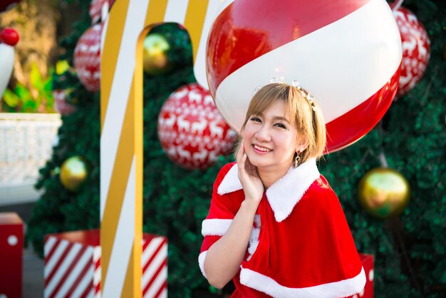 Hermosa mujer asiática joven en ropa de Santa Claus al aire libre Gente de Tailandia Envió felicidad para los niños Feliz Navidad Bienvenido al invierno Fondo de Navidad decorado