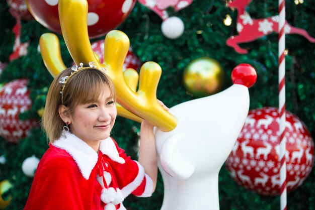 Hermosa mujer asiática joven en ropa de Santa Claus al aire libre Gente de Tailandia Envió felicidad para los niños Feliz Navidad Bienvenido al invierno Fondo de Navidad decorado