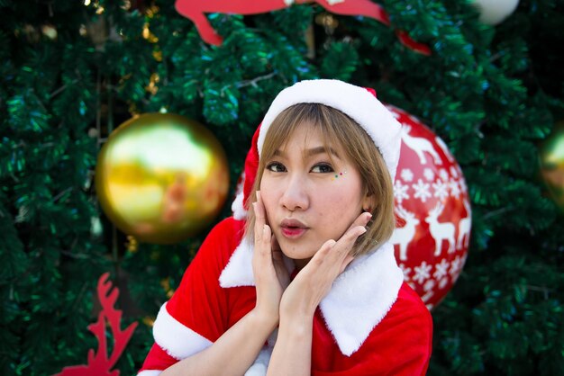 Hermosa mujer asiática joven en ropa de Santa Claus al aire libre Gente de Tailandia Envió felicidad para los niños Feliz Navidad Bienvenido al invierno Fondo de Navidad decorado