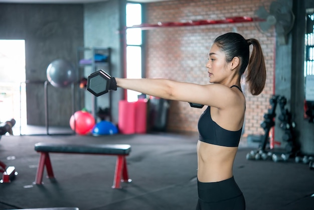 Hermosa mujer asiática juega fitness en el gimnasio. La chica tailandesa tiene un cuerpo delgado. Hora de hacer ejercicio. A la gente le encanta la salud. Estirar el cuerpo antes del entrenamiento.