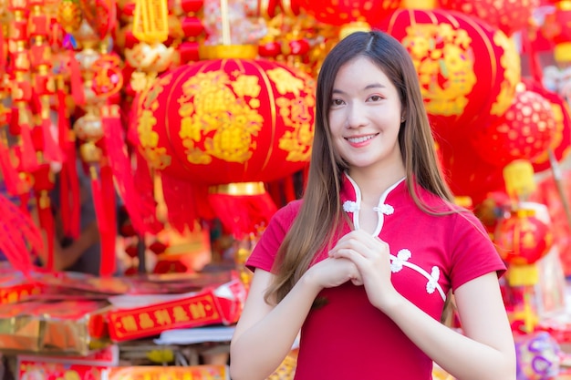 Hermosa mujer asiática de pelo largo lleva un vestido chino rojo o qipao con el tema del año nuevo chino