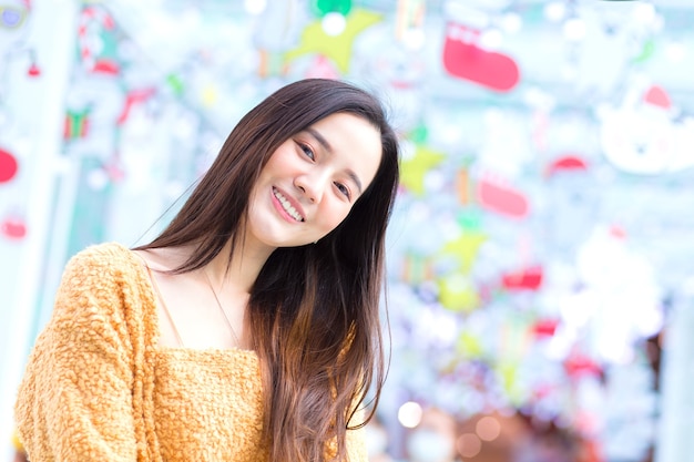 Hermosa mujer asiática con pelo largo viste abrigo amarillo y sonríe feliz