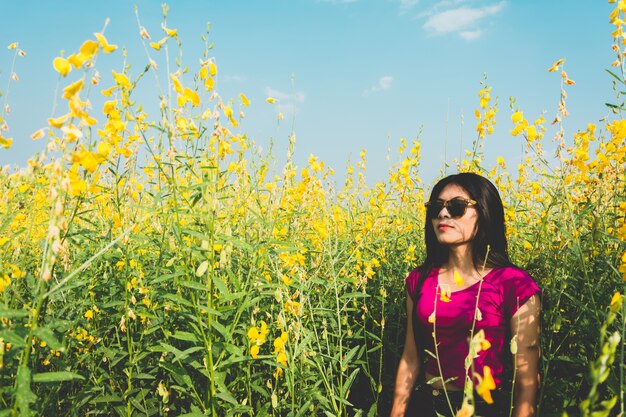 Hermosa mujer asiática de pie en el campo de sunhemp en el campo