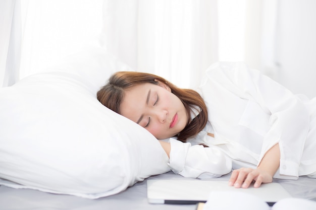 Hermosa mujer asiática con portátil acostado en el dormitorio.