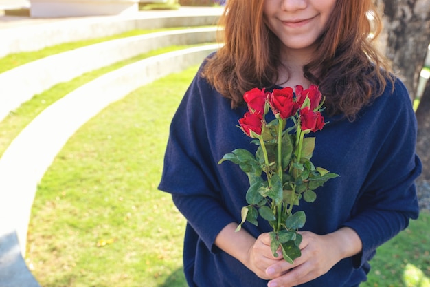 Una hermosa mujer asiática que sostiene la flor de rosas rojas con sentirse feliz en el día de San Valentín