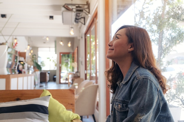 Una hermosa mujer asiática sentada en la cafetería con sentirse feliz