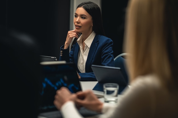 La hermosa mujer asiática sentada a la mesa en reunión de negocios