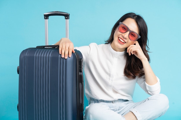 Hermosa mujer asiática sentada posando junto a la maleta y preparándose para viajar
