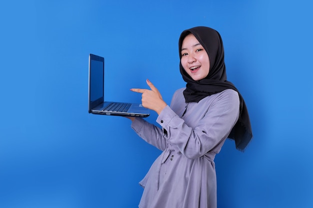 Hermosa mujer asiática sonríe y apunta su computadora portátil