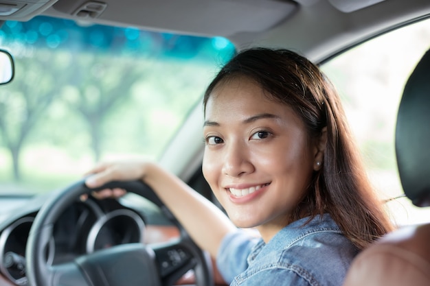 Hermosa mujer asiática sonriendo y disfrutando. Conduciendo un coche en la carretera para viajar