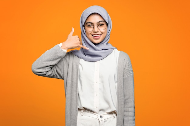 Hermosa mujer asiática sonriendo haciendo gesto de teléfono con la mano