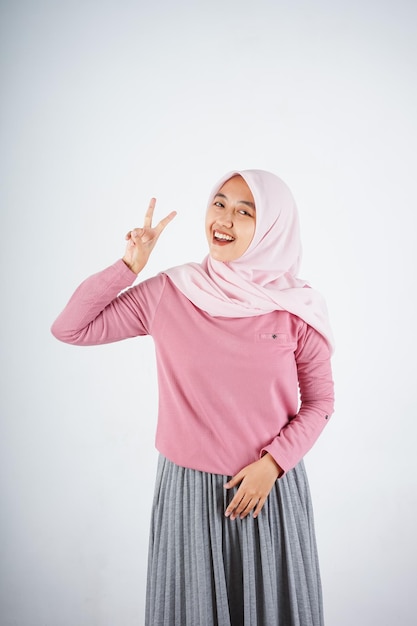 Hermosa mujer asiática sonriente con camiseta rosa y hiyab mostrando y señalando con el dedo