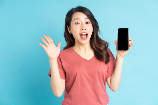 Hermosa mujer asiática sosteniendo el teléfono inteligente en la mano con una expresión alegre