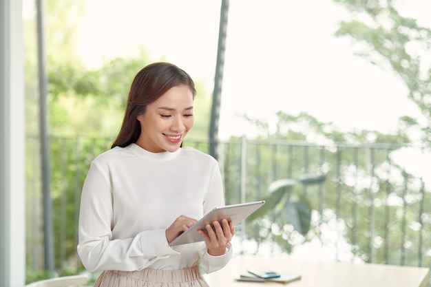 Hermosa mujer asiática con tableta en habitación luminosa