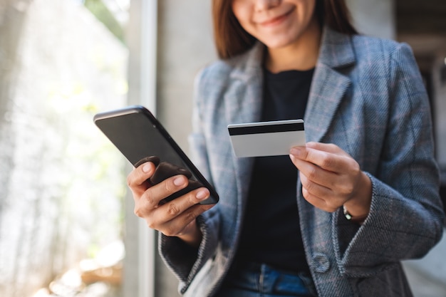 Una hermosa mujer asiática con tarjeta de crédito para comprar y comprar en línea en el teléfono móvil