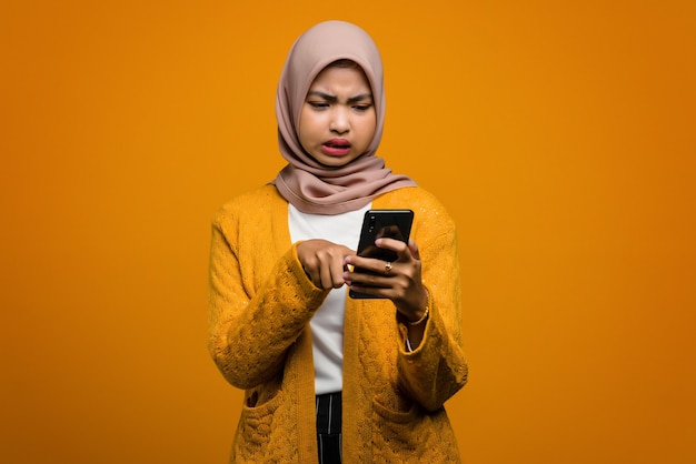 Hermosa mujer asiática con un teléfono inteligente con una cara enojada