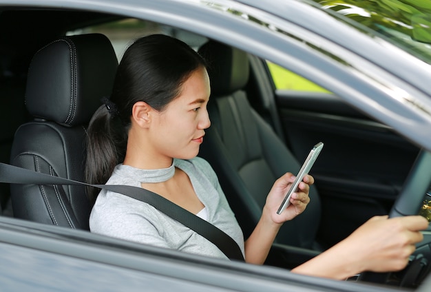 hermosa mujer asiática con teléfono móvil y conducir coche