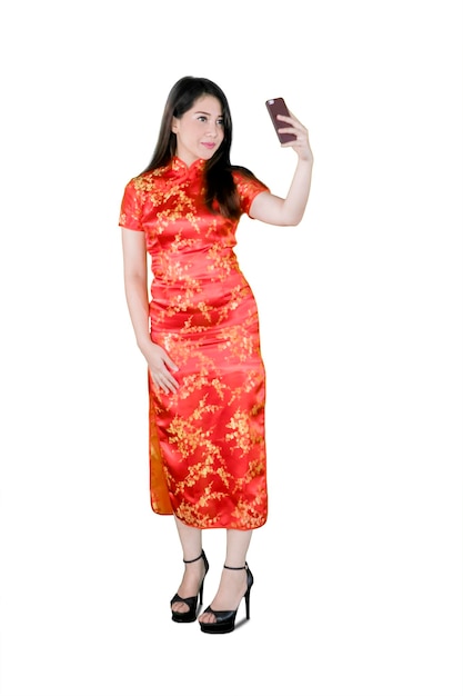 Una hermosa mujer asiática tomando una selfie en un cheongsam