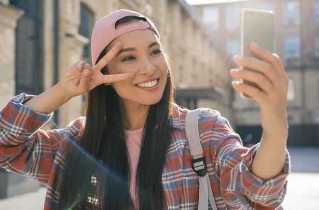 Foto hermosa mujer asiática tomando selfie, mostrando el signo de la victoria