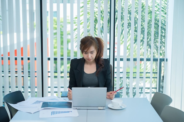 Hermosa mujer asiática trabajando en la oficina por la noche Trabajador de Tailandia trabaja horas extras para la empresa Una mujer de negocios feliz de abastecerse