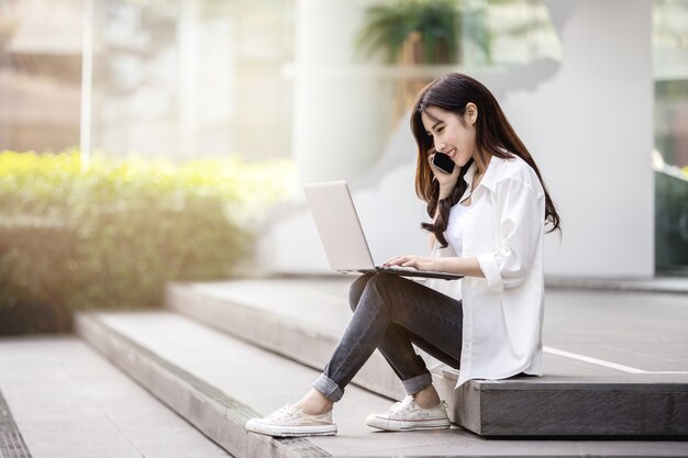 Hermosa mujer asiática trabajando con su computadora portátil mientras está sentado en los pasos
