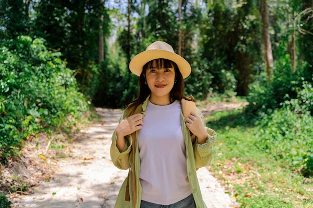 Hermosa mujer asiática travelertravel concepto mujer viajera con mochila sosteniendo sombrero y mirando increíbles montañas y bosques