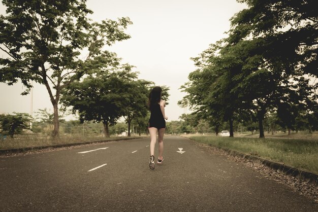 Hermosa mujer asiática trotando en la carretera para quemar grasa en el parque