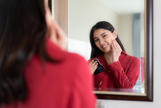 Hermosa mujer asiática vestida de rojo vestido poniendo polvo hojaldre