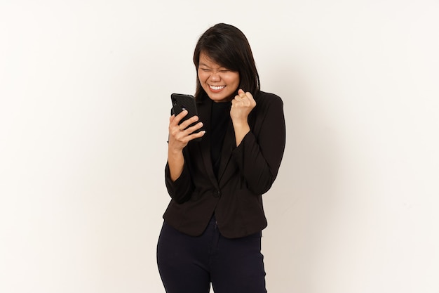 Hermosa mujer asiática vestida con traje negro feliz mientras mira o usa el teléfono inteligente