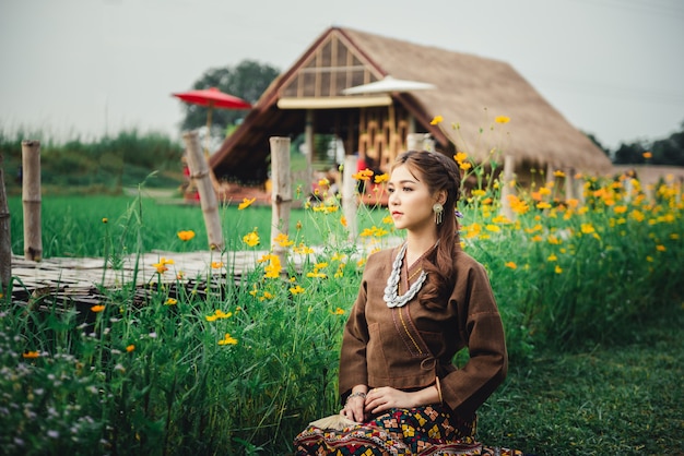 Hermosa mujer asiática con vestido local sentada en el suelo y disfruta de lo natural en el campo de arroz